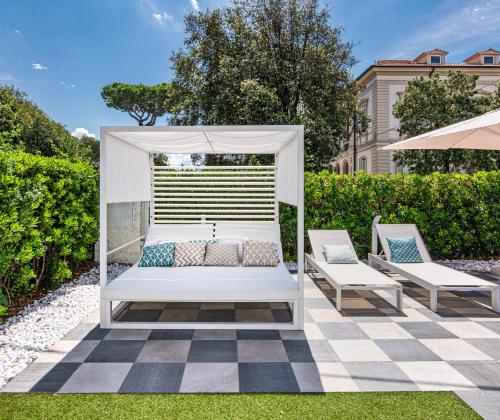 a white bed with two chairs and an umbrella at Hotel Tirreno in Marina di Massa