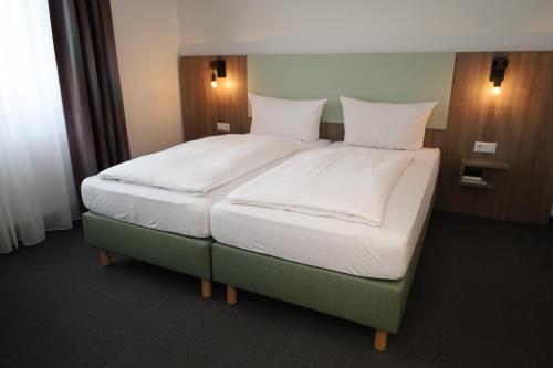 a bedroom with a large bed with white sheets and pillows at Hotel-Restaurant Thomsen in Delmenhorst