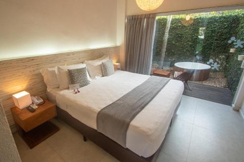 a bedroom with a large bed and a large window at Serena Buzios in Búzios
