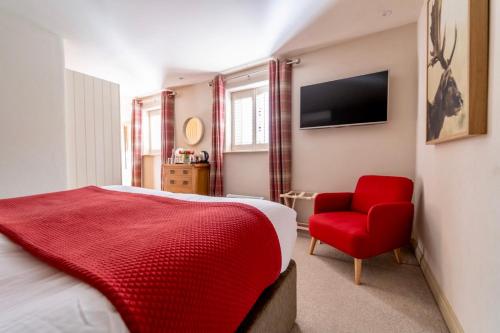 a bedroom with a red bed and a red chair at The Honingham Buck in Norwich
