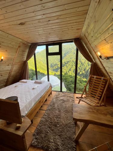 ein Schlafzimmer mit einem Bett und einem Stuhl in einem Zimmer in der Unterkunft Mtirala Skhivi Cottage in Batumi