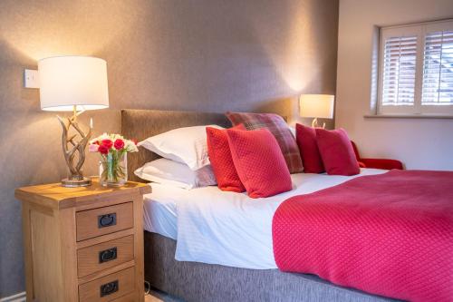 a bedroom with a bed with red and white pillows at The Honingham Buck in Norwich