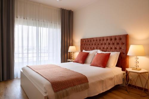 a bedroom with a large bed with red pillows and a window at Gaia Douro Apartment in Vila Nova de Gaia