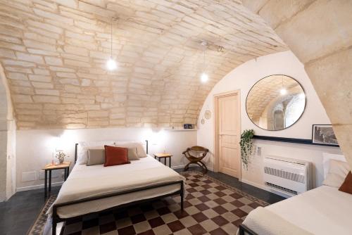 a bedroom with two beds and a stone wall at Officine degli Aromi in Ragusa