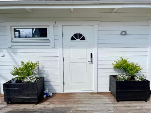 a white door on a house with two potted plants at Studion in Falun