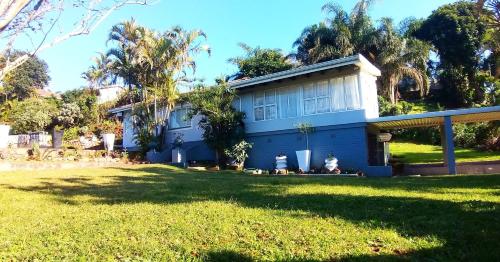 a blue house with a lawn in front of it at Rose Holiday Home in Durban