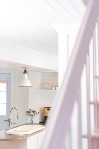 a white kitchen with a sink and a window at Le Boulevard par Maison Dudley in Lac-Mégantic