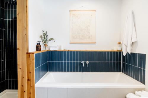 uma banheira na casa de banho com azulejos azuis em Le Boulevard par Maison Dudley em Lac-Mégantic