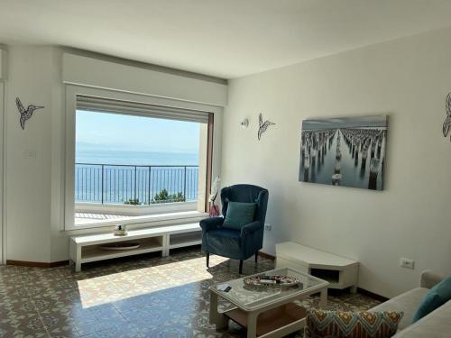 a living room with a chair and a large window at Finestra sul mare in Monfalcone