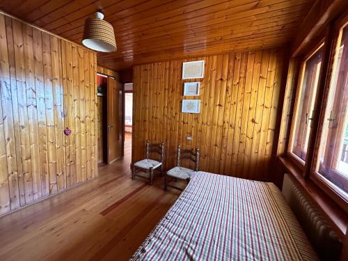 a room with wooden walls and a bed and two chairs at L'Atelier du Temps - Sole e Luna in Cogne