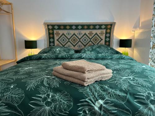 ein Bett mit einer grünen Tagesdecke und Handtüchern darauf in der Unterkunft Jeleni Ruczaj in Karpacz