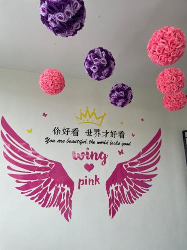 a sign with two wings and words writing pink at Yes Muar in Muar