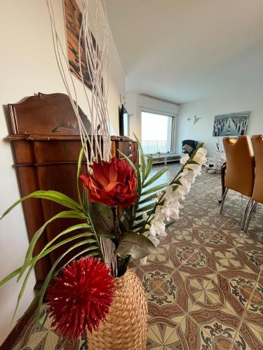 a room with a vase with red flowers in it at Finestra sul mare in Monfalcone