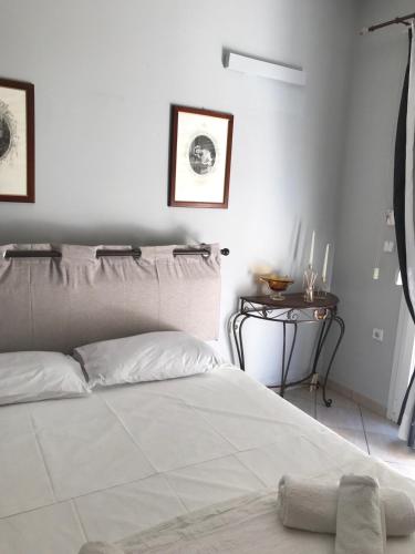 a white bedroom with a bed and a side table at Haplotēs Rhodes Studio in Koskinou