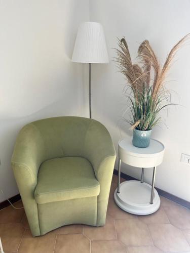 a green chair and a table with a lamp and a plant at Finestra sul mare in Monfalcone