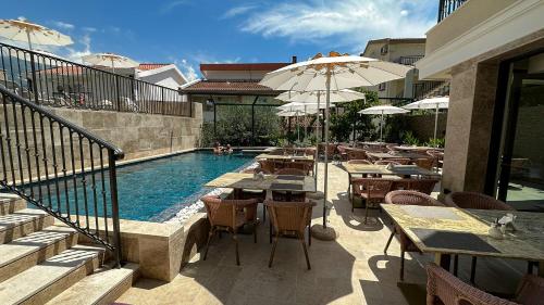 a swimming pool with tables and umbrellas next to a restaurant at Hotel Pima Budva in Budva