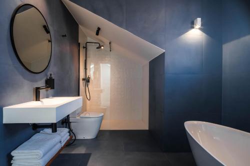 a bathroom with a sink and a mirror and a tub at Apartamentos El Reloj in Luanco