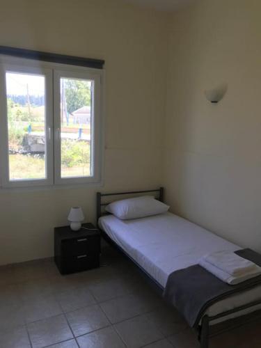 a bedroom with a bed and two windows at Rouvas Beach House in Sidari