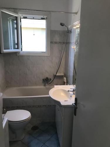 a bathroom with a sink and a toilet and a window at Rouvas Beach House in Sidari