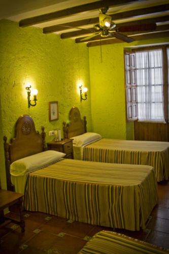 a room with three beds in a green room at Hotel Hermanos Macias in Ronda