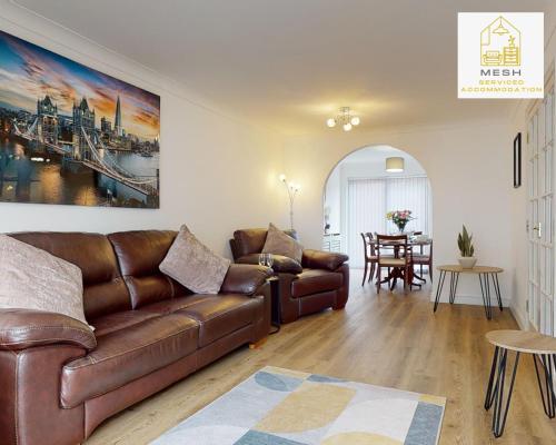 a living room with a brown leather couch and a table at Ashford Home with 3 Bedrooms, Ideal for Contractors by Mesh Accommodation in Ashford