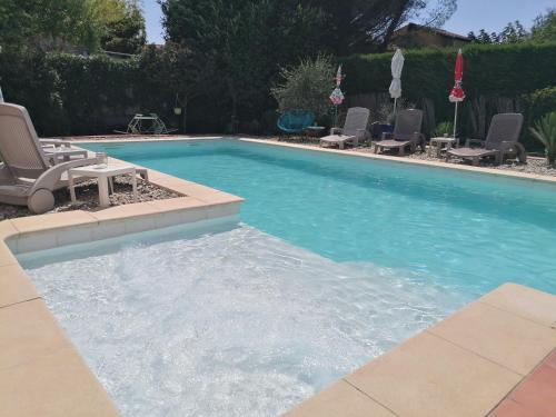 - une piscine avec des chaises longues dans l'établissement Villa chaleureuse avec piscine, à Saint-Alexandre