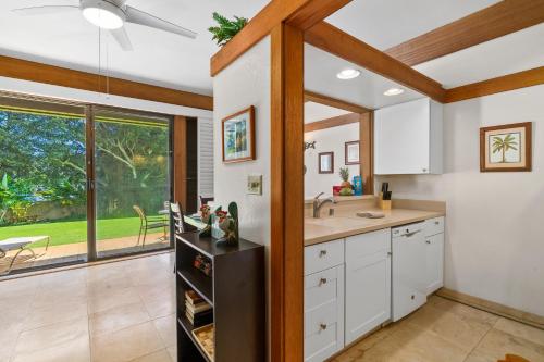 a kitchen with white cabinets and a large window at 1st Floor Kiahuna 1br Condo, Garden View, Athletic Club KP422 in Koloa