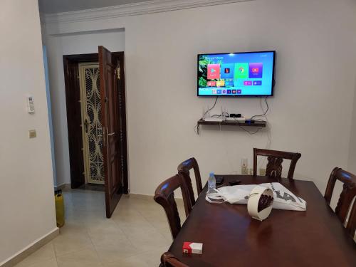 a dining room with a table and a television on a wall at Zemmouri in Tangier