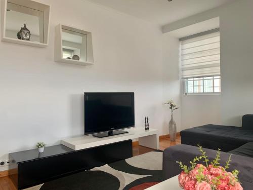 a living room with a flat screen tv on a white wall at Retiro das Bananeiras in Horta
