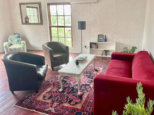 a living room with a red couch and two chairs at Loft on Long in Hermanus