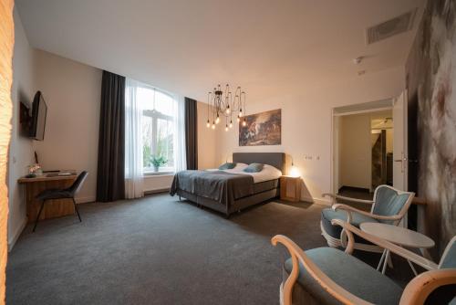 um quarto com uma cama, uma mesa e cadeiras em Boutique hotel & brasserie de Heerlyckheid em Bredevoort