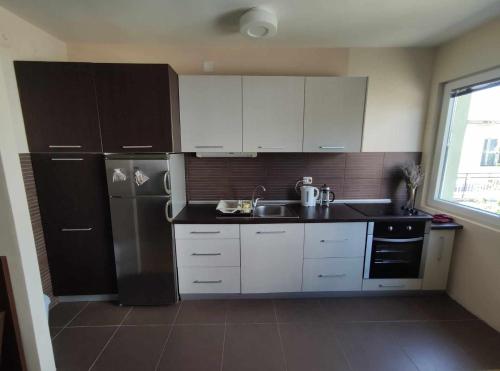 a kitchen with white cabinets and a stainless steel refrigerator at Cozy Apartment Palazzo in Ohrid