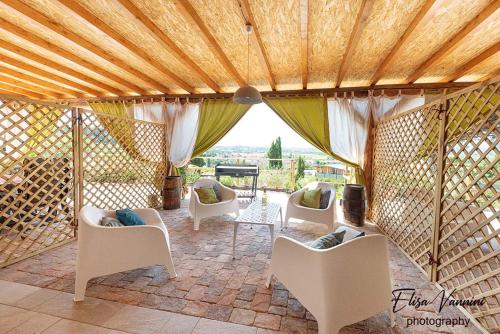 a living room with white chairs and a wooden ceiling at La casa delle Rondini in Forcoli