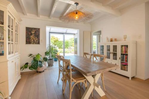 uma sala de jantar com uma mesa de madeira e cadeiras em Gezellig huisje met leuke tuin em De Haan