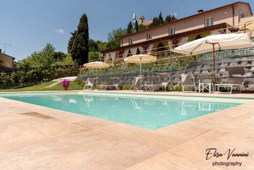 a swimming pool in front of a building with chairs and umbrellas at La casa delle Rondini in Forcoli