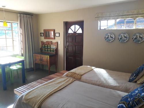 a bedroom with two beds and a table and window at Kaltenbach Cottages in Magoebaskloof