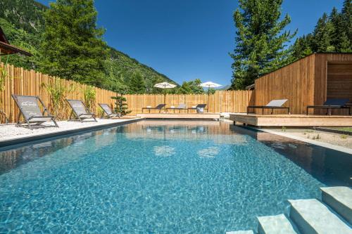 a swimming pool with chairs and a wooden fence at AlpinSpa zur Post - Bergbahn im Sommer 2025 inklusive in Bad Gastein