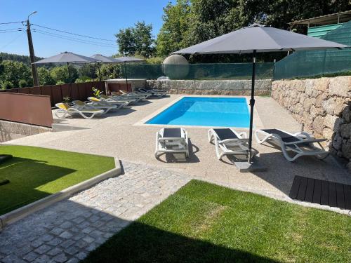 a swimming pool with lounge chairs and an umbrella at Casa do capitão A casa ideal para férias no Gerês in Vieira do Minho