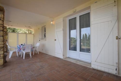 - une terrasse couverte avec une table, des chaises et une porte dans l'établissement SETTE B Locations T1 Bas Villa, à Cavalaire-sur-Mer