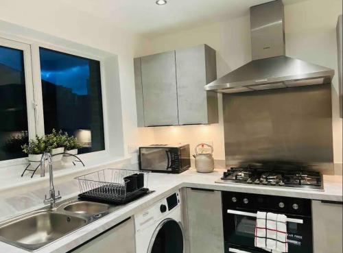 a kitchen with a sink and a stove top oven at Stylish New Built in Manchester