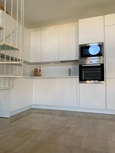 a kitchen with white cabinets and a microwave at Regina Elena, Luminoso appartamento sulla spiaggia in Calambrone