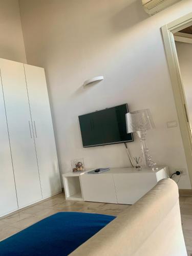 a white living room with a tv and a blue rug at Regina Elena, Luminoso appartamento sulla spiaggia in Calambrone