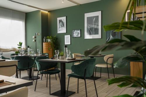 a restaurant with green walls and tables and chairs at Mercure Milano Agrate Brianza in Agrate Brianza