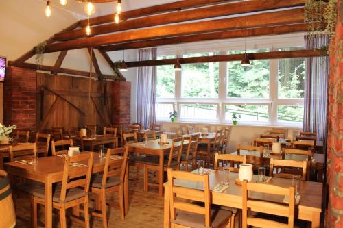 restauracja z drewnianymi stołami, krzesłami i oknami w obiekcie Resort Lesní Lázně w mieście Zvánovice