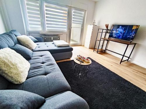 salon z niebieską kanapą i telewizorem w obiekcie BeBu - Apartment w mieście Friedrichshafen
