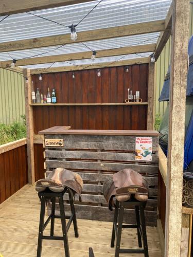 a bar with two stools with hats on them at Horse Truck Tiny Home in Swords