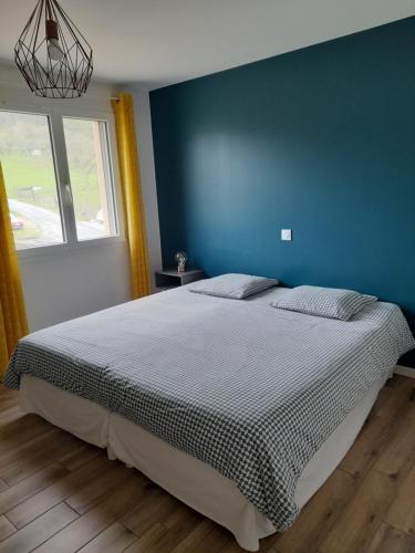 a bedroom with a large bed with a blue wall at Gite des Cépages in Voiteur