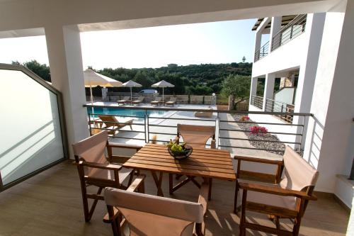 balcón con mesa de madera y sillas y piscina en Michelangelo suites and apartments en Valanidorachi