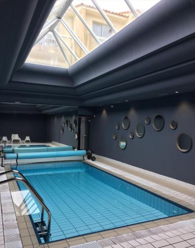 an indoor swimming pool with blue tiles on the floor and a window at Logis Hôtel Le Calluna Restaurant La Flottille in Préfailles