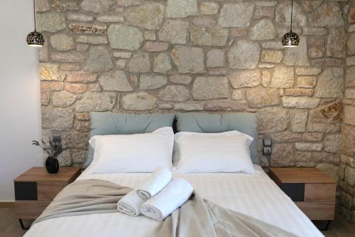 a bedroom with a stone wall and a bed with towels at Michelangelo suites and apartments in Valanidorachi